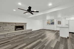 Unfurnished living room featuring ceiling fan, dark hardwood / wood-style flooring, and a fireplace