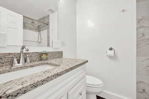 Bathroom with vanity, toilet, and tiled shower