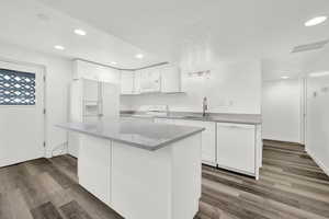 Kitchen featuring dark hardwood / wood-style flooring, white cabinetry, sink, and white appliances