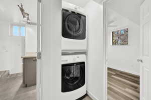 Washroom featuring light wood-type flooring and stacked washing maching and dryer