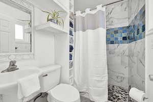 Bathroom featuring toilet, sink, and a shower with shower curtain