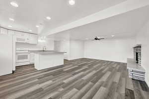 Kitchen with white appliances, ceiling fan, sink, white cabinets, and hardwood / wood-style floors