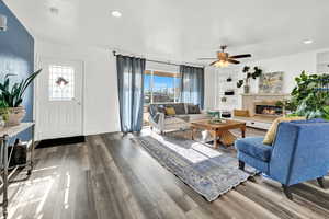 Living room with hardwood / wood-style flooring, built in shelves, a healthy amount of sunlight, and ceiling fan