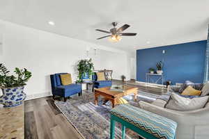 Living room with ceiling fan and hardwood / wood-style flooring