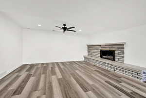 Unfurnished living room featuring ceiling fan, a fireplace, and light wood-type flooring