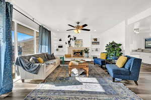 Living room with built in shelves, ceiling fan, and dark hardwood / wood-style floors