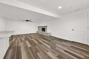 Unfurnished living room featuring a fireplace, dark hardwood / wood-style flooring, and ceiling fan