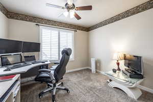 Carpeted home office featuring ceiling fan