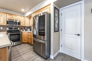 Kitchen featuring backsplash, light brown cabinets, stainless steel appliances, and light wood-type flooring