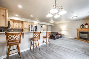 Kitchen with light brown cabinets, a kitchen breakfast bar, backsplash, stainless steel fridge, and light hardwood / wood-style floors