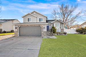 View of front of property featuring a front yard, a garage, and central AC unit