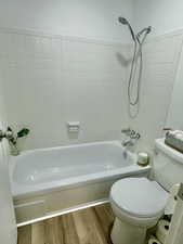 Bathroom with toilet, hardwood / wood-style floors, and tiled shower / bath