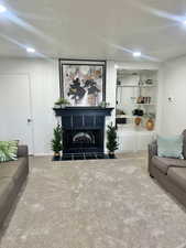 Carpeted living room featuring a large fireplace and a textured ceiling