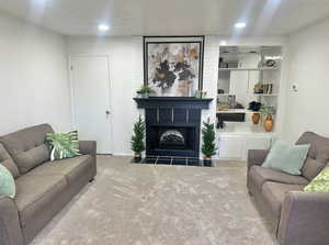 Carpeted living room with a textured ceiling and a large fireplace