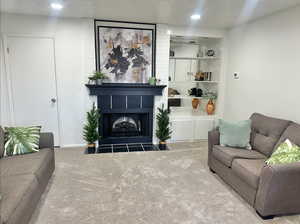 Living room featuring a large fireplace, carpet, and a textured ceiling