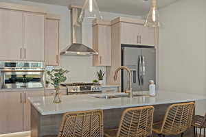 Kitchen with appliances with stainless steel finishes, backsplash, sink, wall chimney range hood, and light brown cabinets