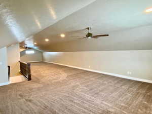 Bonus room with carpet flooring, ceiling fan, lofted ceiling, and a textured ceiling