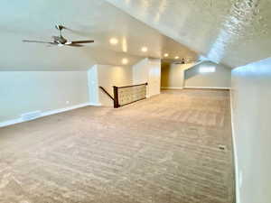 Bonus room with carpet, ceiling fan, a textured ceiling, and vaulted ceiling