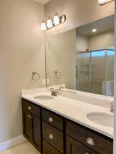 Bathroom featuring tile patterned flooring, vanity, and a shower with door