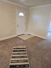 Foyer featuring light colored carpet and crown molding