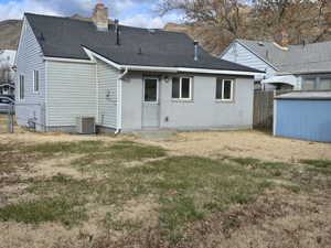 Back of house with a yard and central AC unit