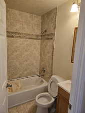 Full bathroom with tile patterned floors, vanity, a textured ceiling, toilet, and tiled shower / bath