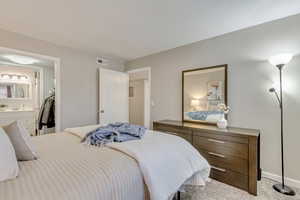 Bedroom featuring ensuite bathroom and light carpet