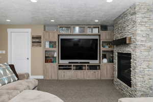 Living room featuring carpet and a stone fireplace