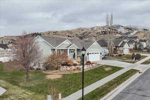 View of front of house with a mountain view, a front yard, and a garage