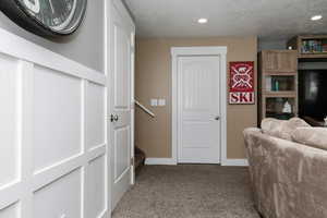 Hallway with a textured ceiling and light carpet