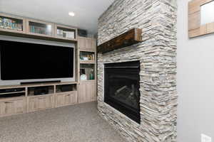 Unfurnished living room featuring a fireplace, carpet, and a textured ceiling