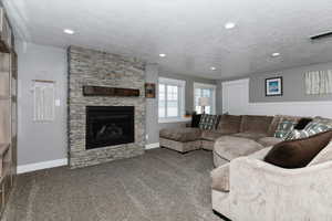 Living room featuring a textured ceiling, carpet floors, and a fireplace