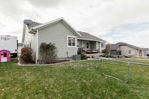 Back of property featuring a lawn, an outdoor living space, and central air condition unit