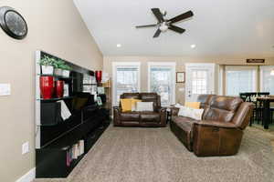 Carpeted living room featuring ceiling fan and vaulted ceiling