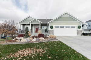 Craftsman house featuring a front lawn, covered porch, and a garage