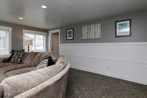 Living room featuring a textured ceiling and dark carpet