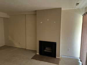 Unfurnished living room with a tile fireplace, carpet, and a textured ceiling