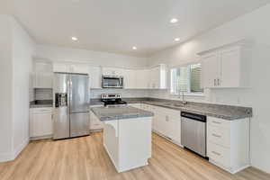 Kitchen featuring white cabinets, sink, light hardwood / wood-style flooring, a kitchen island, and stainless steel appliances