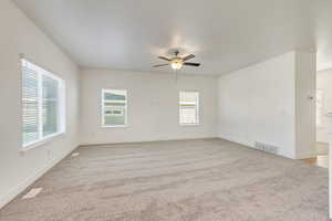 Empty room featuring light carpet, plenty of natural light, and ceiling fan