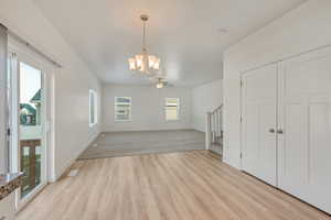 Interior space featuring ceiling fan with notable chandelier and light carpet