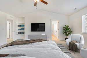 Carpeted bedroom with ceiling fan, ensuite bathroom, and vaulted ceiling