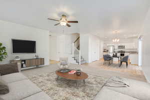 Living room with ceiling fan with notable chandelier, light wood-type flooring, and sink