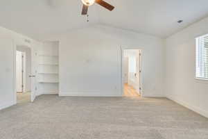 Spare room with light carpet, vaulted ceiling, ceiling fan, and built in features