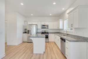 Kitchen with sink, a kitchen island, stainless steel appliances, and light hardwood / wood-style flooring