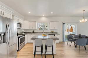 Kitchen featuring a healthy amount of sunlight, light wood-type flooring, white cabinetry, and appliances with stainless steel finishes