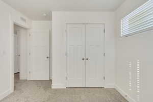 Unfurnished bedroom featuring light carpet and a closet