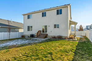 Back of house with central air condition unit and a yard