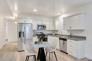 Kitchen featuring white cabinets, sink, stainless steel appliances, and light hardwood / wood-style flooring