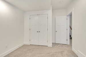 Unfurnished bedroom featuring light carpet and a closet