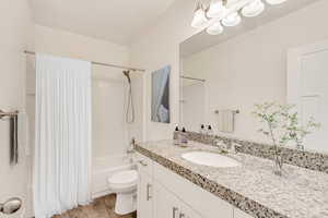 Full bathroom with vanity, hardwood / wood-style flooring, toilet, and shower / bath combo with shower curtain